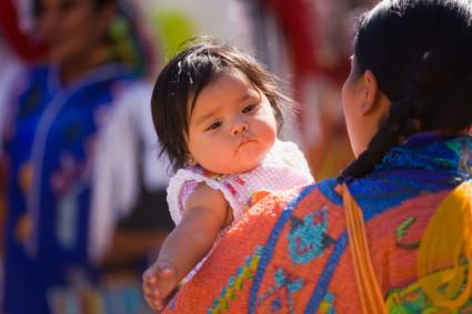 Female Traditional Dancer holds a baby Chumash Inter Tribal Powwow Santa Ynez Valley near Santa Barbara California