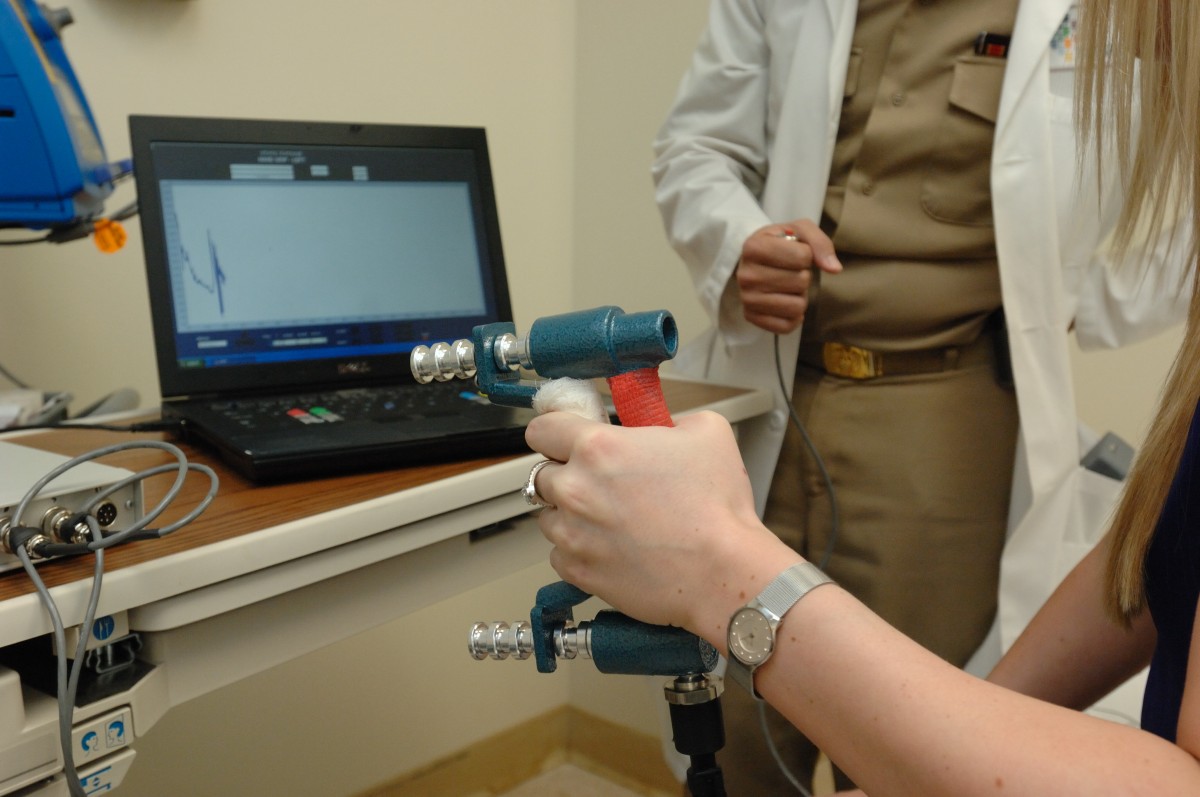 Patient squeezes a decide that measures grip strength
