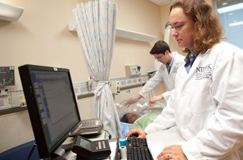 Postdoctoral Fellow Stephanie Goodwin (right) and Postbaccalaureate Fellow Thomas Bemis prepare to measure a research participant’s resting energy expenditure with a ventilated hood